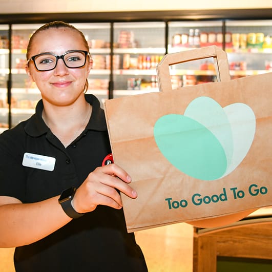 Member of staff holding a Too Good To Go bag
